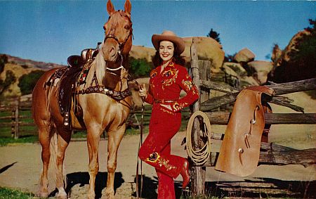 Postcard of a cowgirl posing with her horse.